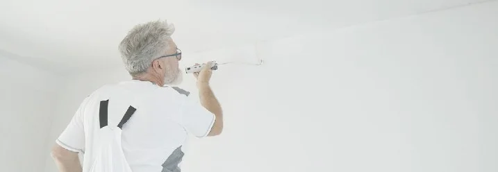 Person streicht Wand mit Farbrolle